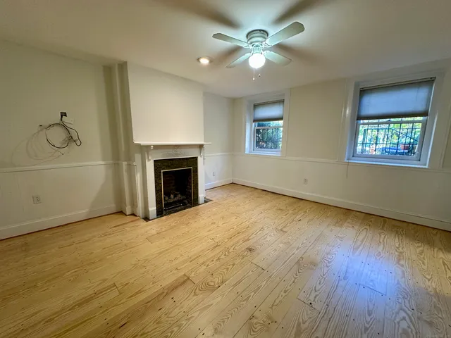 an empty room with windows fireplace and wooden floor