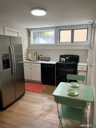 a kitchen with stainless steel appliances granite countertop a sink a stove a refrigerator a dining table and chairs