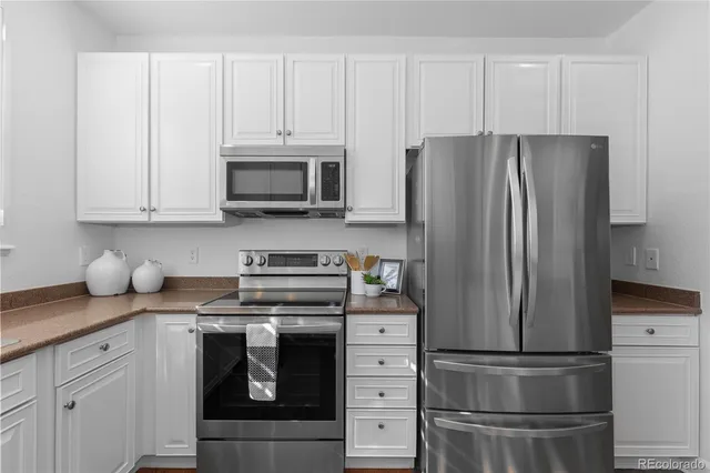 a kitchen with granite countertop a refrigerator stove and microwave