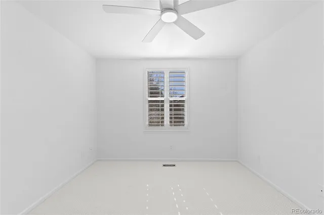 an empty room with a window and a fan