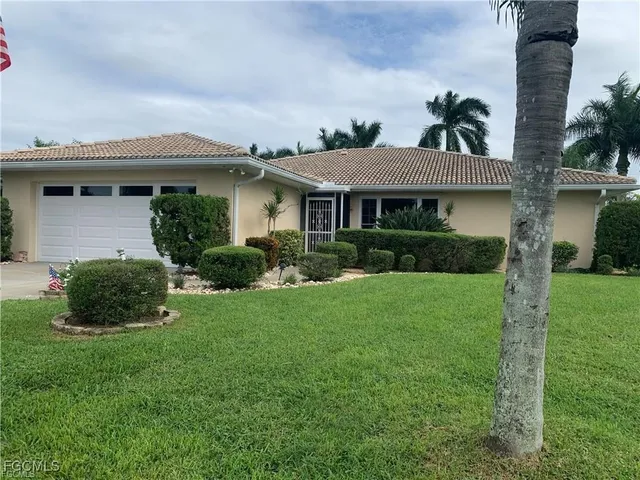 a front view of a house with a yard and potted plants