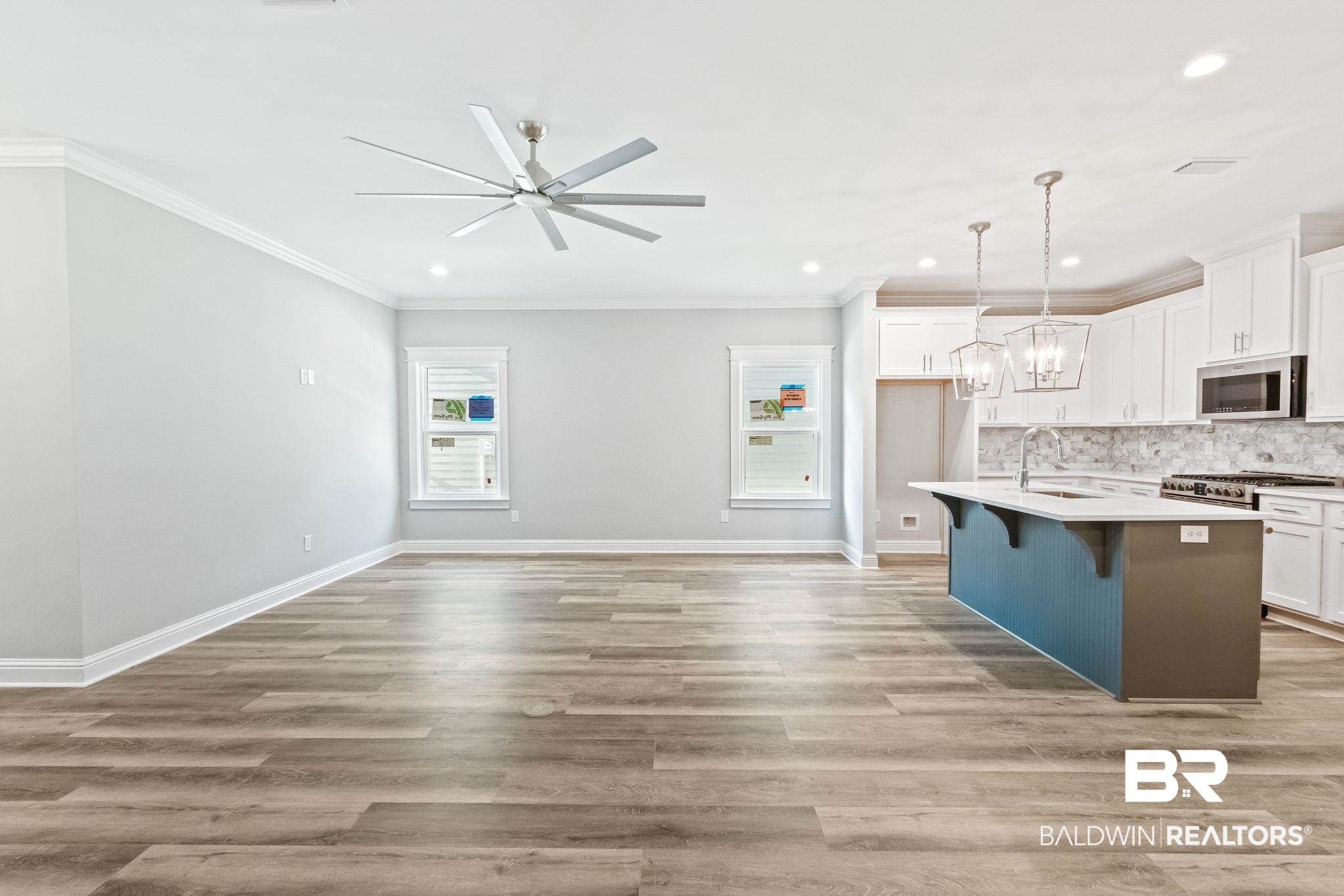 12441 Reunion Place Foley, AL 36535 - Photo 10 of 31 Kitchen with ceiling fan with notable chandelier, appliances with stainless steel finishes, a kitchen island with sink, light hardwood / wood-style floors, and backsplash