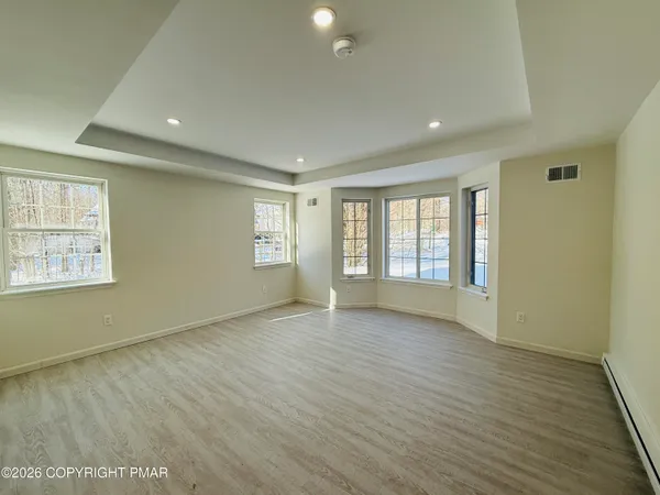 an empty room with wooden floor and windows