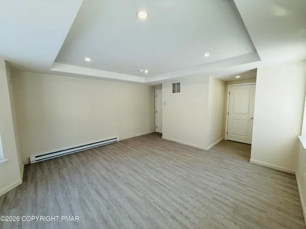 an empty room with wooden floor and windows