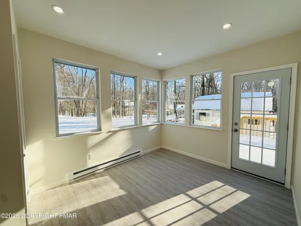a view of an empty room with a window and wooden floor