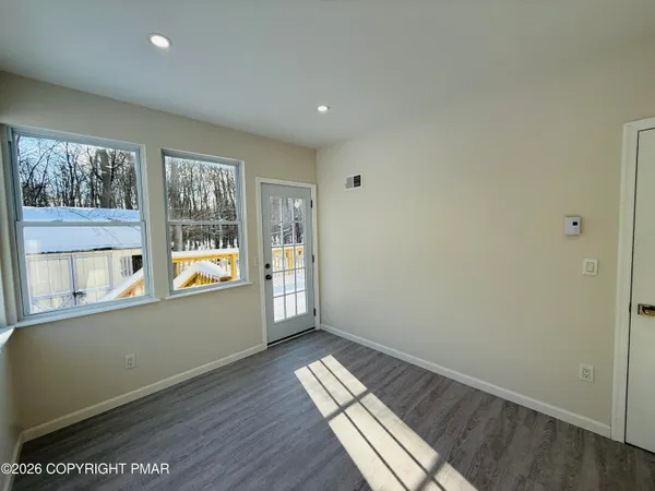 an empty room with wooden floor and windows