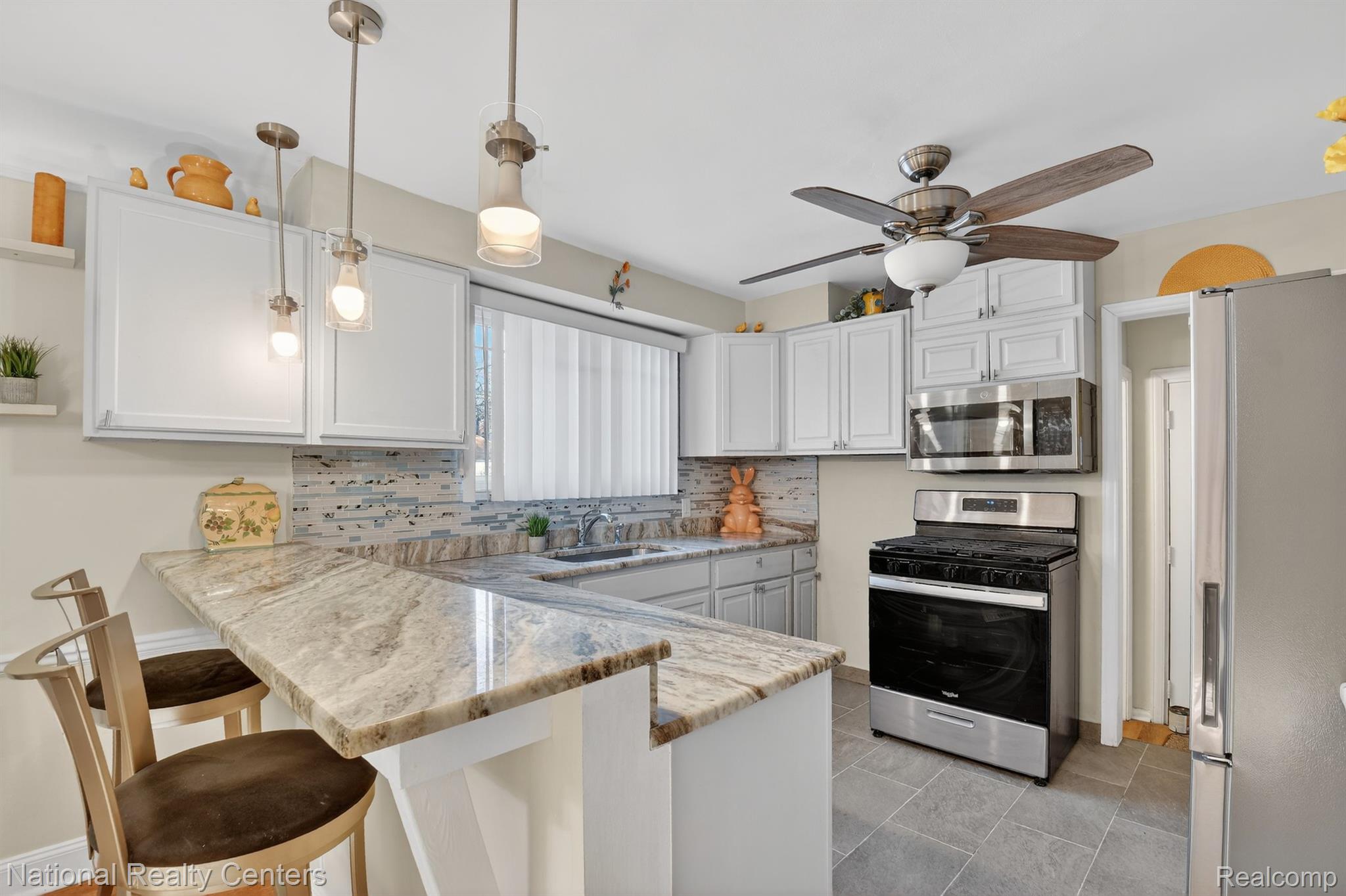 3956 Harvard Road Detroit, MI 48224 - Photo 16 of 44 Kitchen with stainless steel appliances, pendant lighting, white cabinetry, and a peninsula