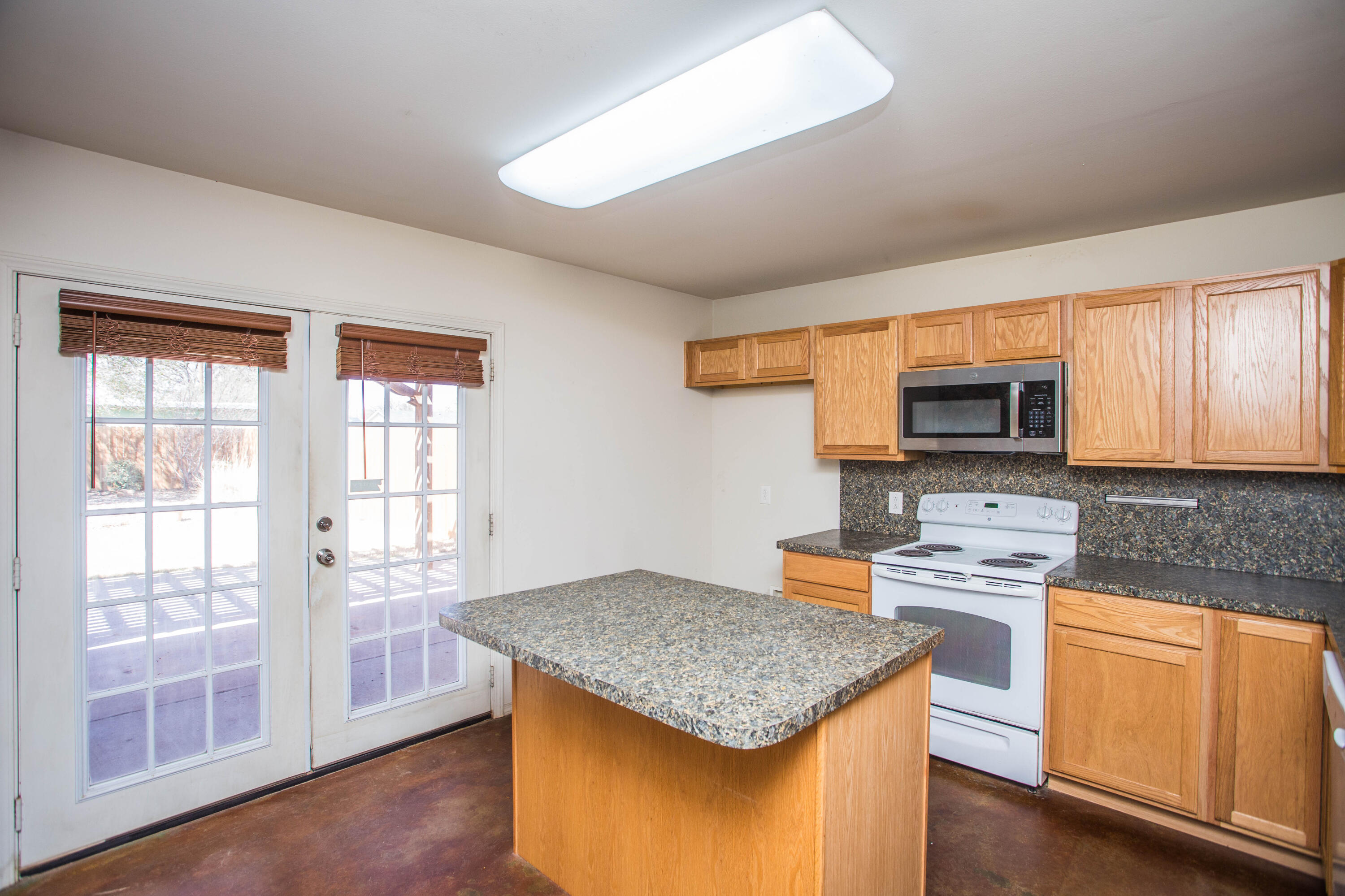 6114 22nd Street, Unit 2 Lubbock, TX 79407 - Photo 14 of 48 a kitchen with stainless steel appliances granite countertop a stove top oven a sink dishwasher a microwave oven and a dining table with wooden floor