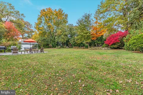 a view of a house with a yard and large tree