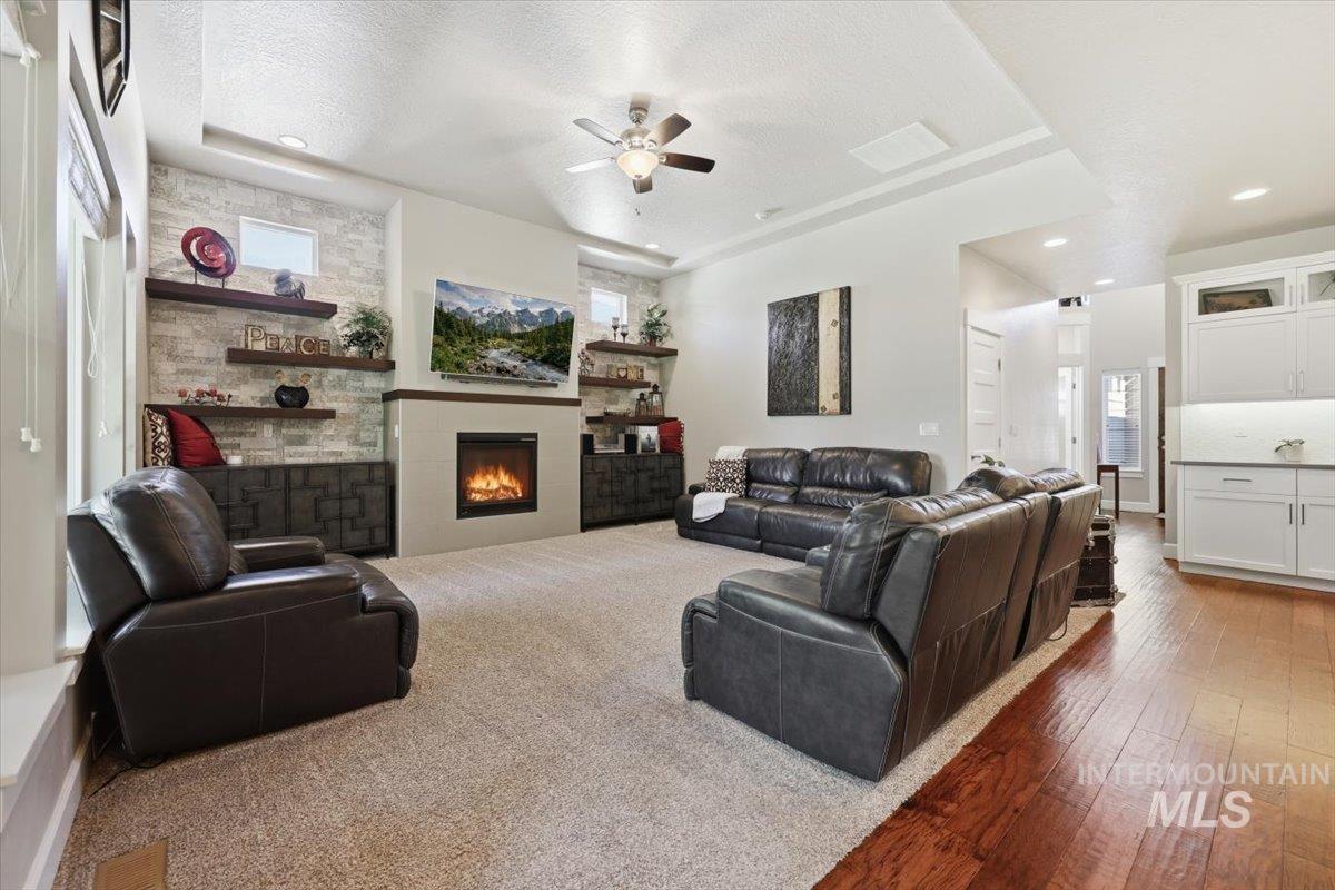 1303 West Brando Street Meridian, ID 83646 - Photo 18 of 49 Spacious living area featuring a stone accent wall with built-in fireplace, cathedral ceilings with a ceiling fan, and recessed lighting