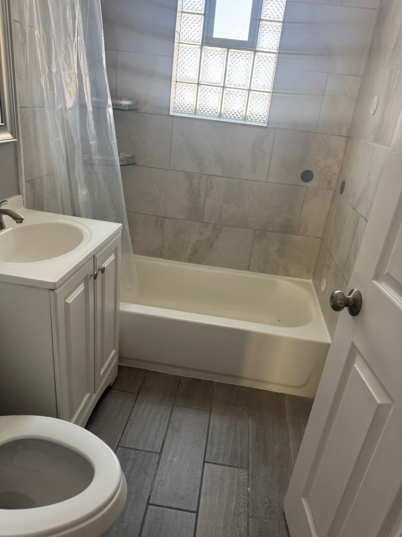 654 East 105th Street Chicago, IL 60628 - Photo 8 of 12 a bathroom with a bathtub a window and a shower