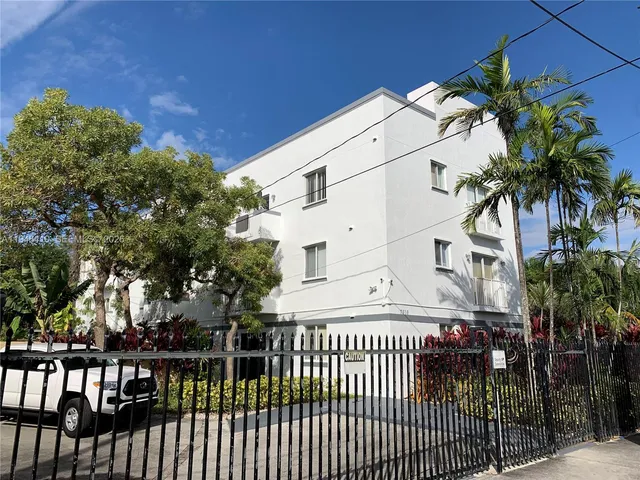 a view of a white house with a small yard and plants