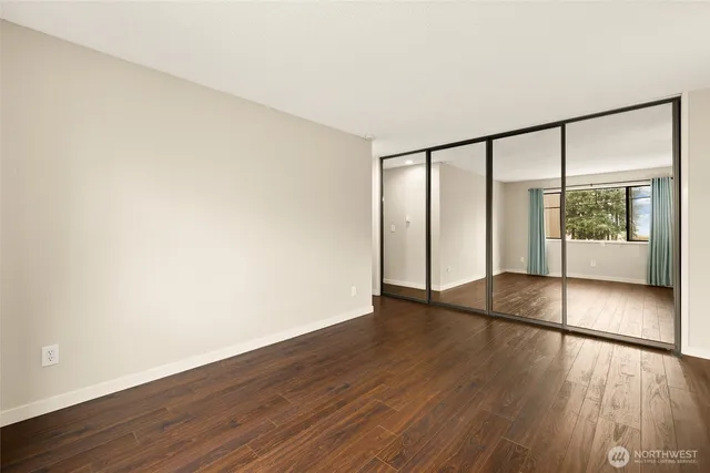 a view of an empty room with wooden floor and a window