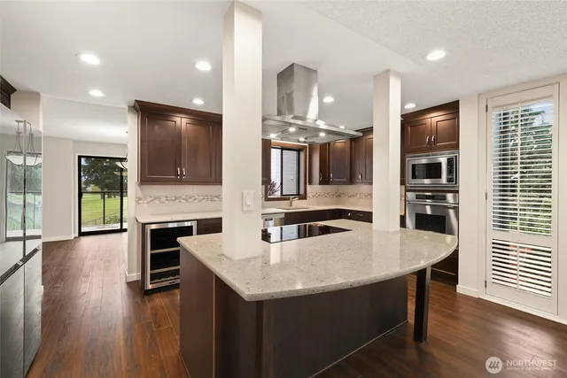 an open kitchen with granite countertop kitchen island wooden floor center island and stainless steel appliances