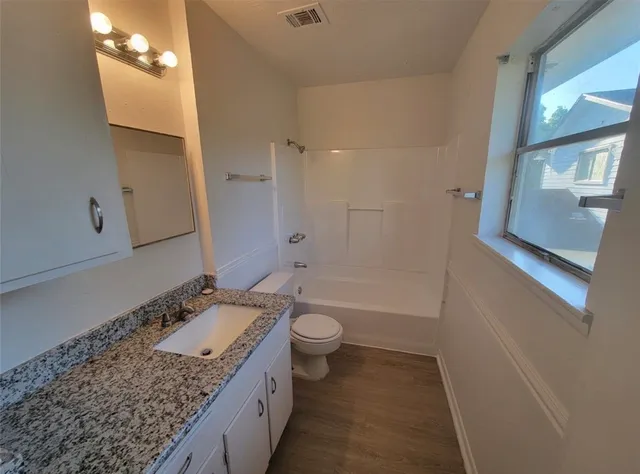 a utility room with granite countertop a sink and a wooden floor