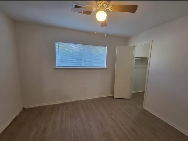 an empty room with wooden floor and fan