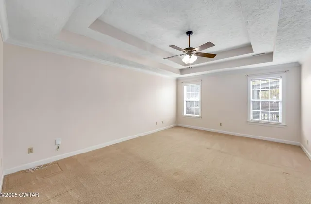 an empty room with windows and chandelier fan