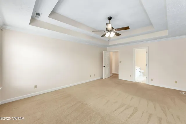 an empty room with chandelier fan and windows