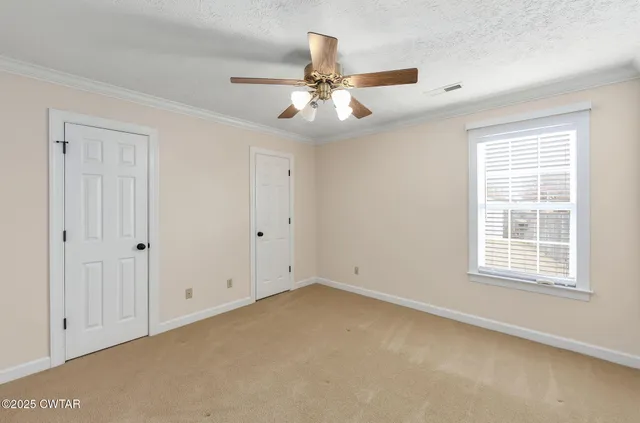 an empty room with chandelier fan and windows
