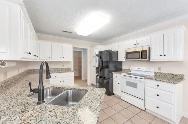 a kitchen with granite countertop a sink stove and refrigerator