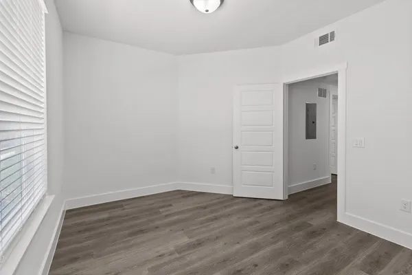 a view of a hallway with wooden floor and a bathroom