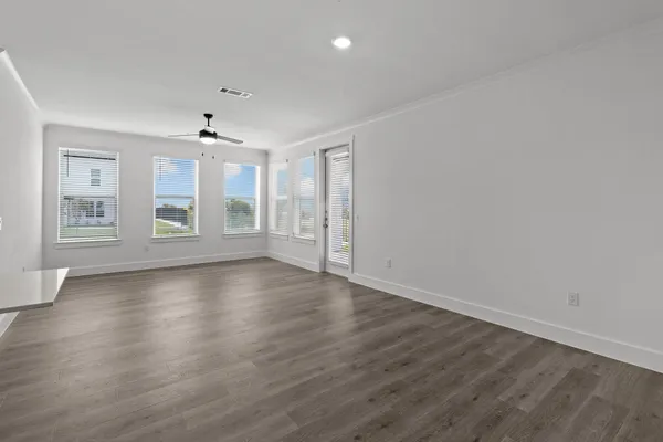a view of an empty room with a window and wooden floor