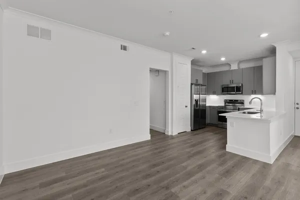 a large white kitchen with stainless steel appliances granite countertop a refrigerator a sink dishwasher a stove and a dining table with wooden floor