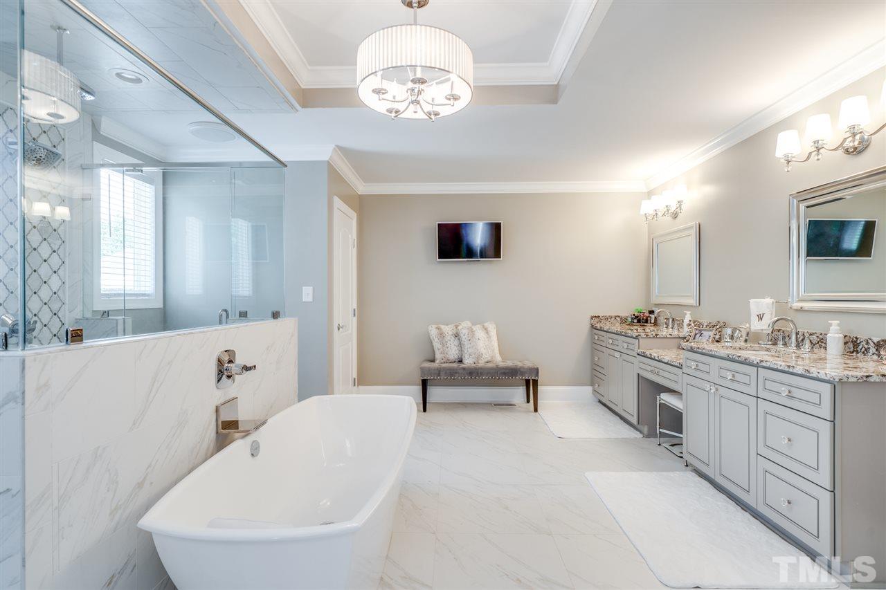 2256 Sanders Road Stem, NC 27581 - Photo 13 of 29 a spacious bathroom with a double vanity sink a mirror a bathtub and a window