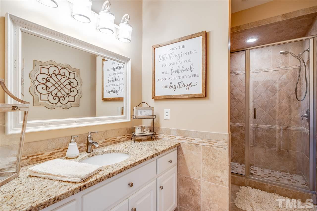 2256 Sanders Road Stem, NC 27581 - Photo 15 of 29 a bathroom with a granite countertop sink a mirror and a shower