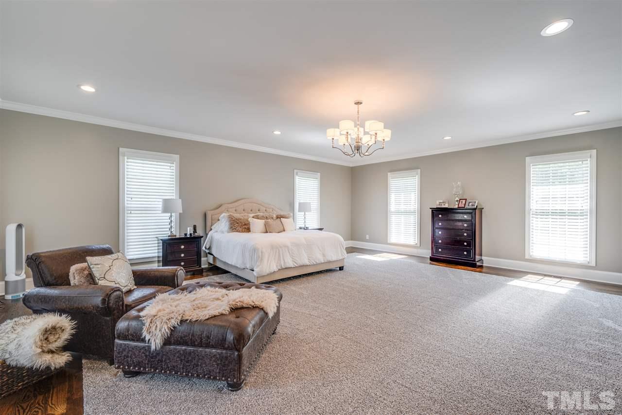 2256 Sanders Road Stem, NC 27581 - Photo 9 of 29 a spacious bedroom with a bed and a chandelier