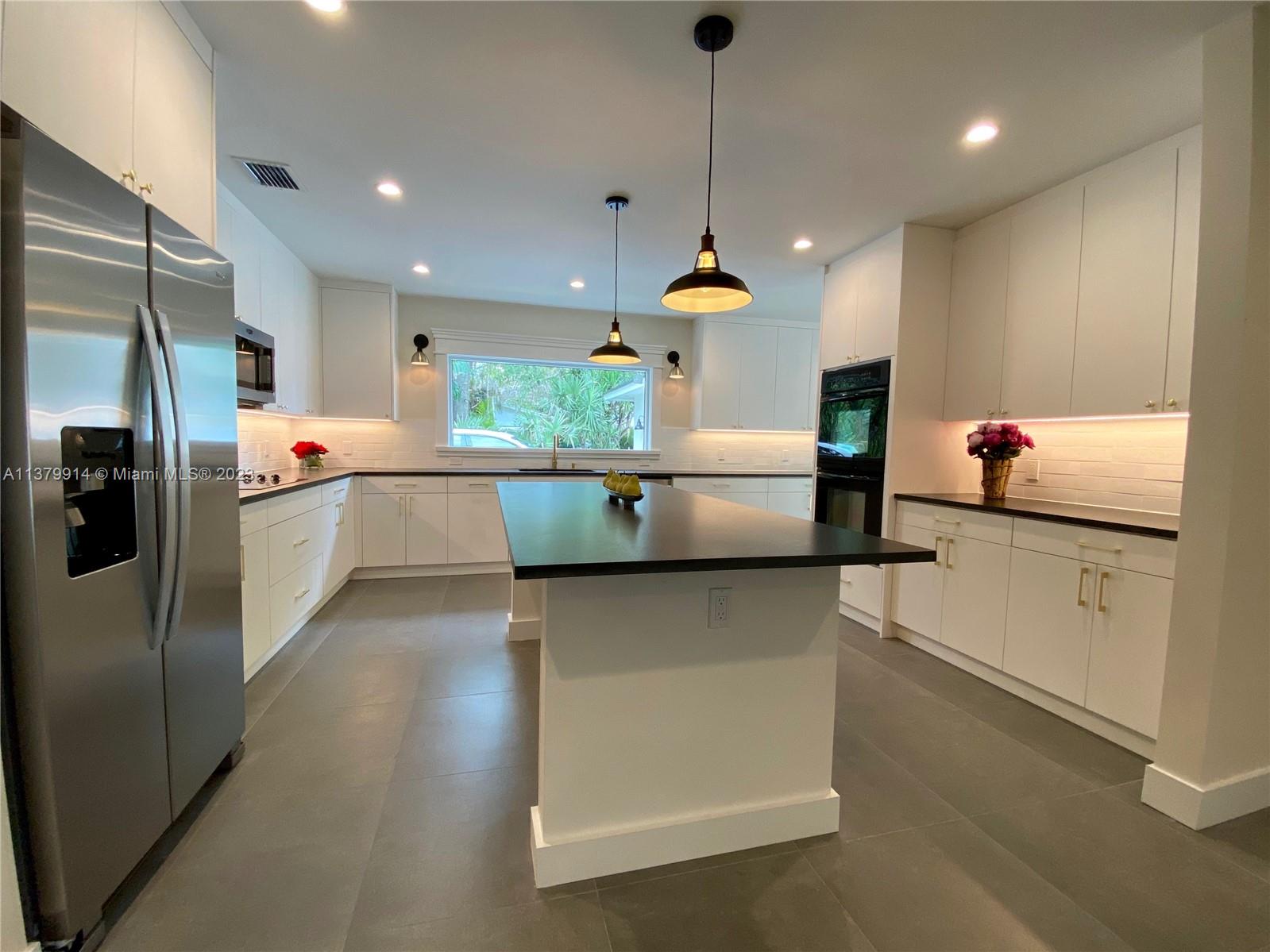 11821 Southwest 81st Road, Unit 11821 Pinecrest, FL 33156 - Photo 4 of 14 a kitchen with stainless steel appliances a sink a stove a refrigerator and blue cabinets with wooden floor