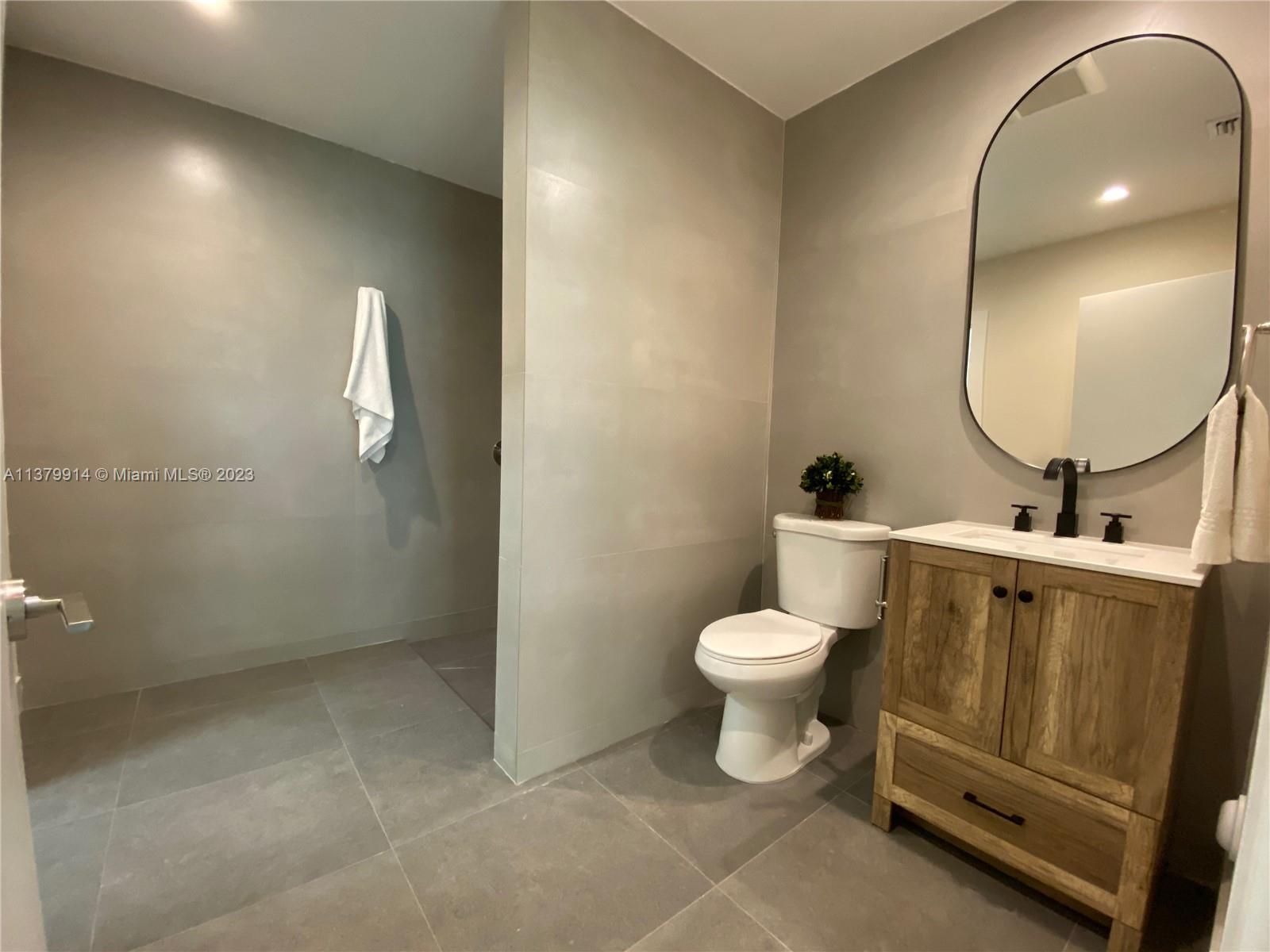 11821 Southwest 81st Road, Unit 11821 Pinecrest, FL 33156 - Photo 10 of 14 a bathroom with a toilet sink and mirror