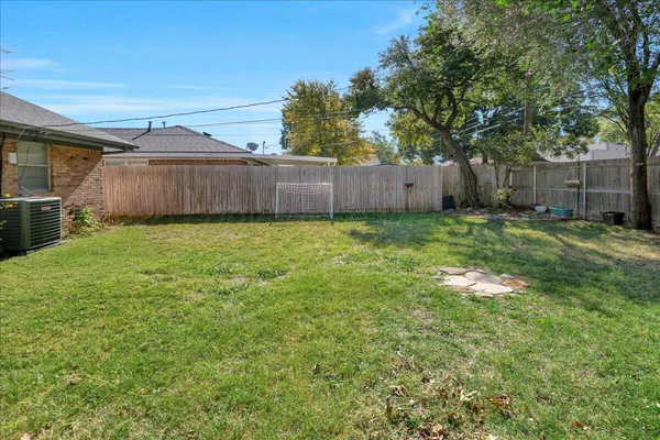 a view of a backyard with wooden fence and a large tree