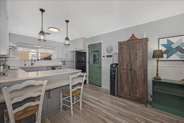 a kitchen with stainless steel appliances granite countertop a refrigerator a microwave oven a stove and a dining table with wooden floor