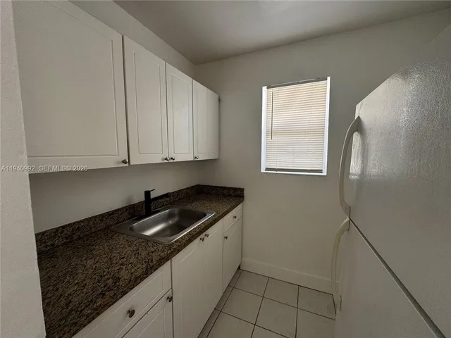 a kitchen with granite countertop white cabinets and sink