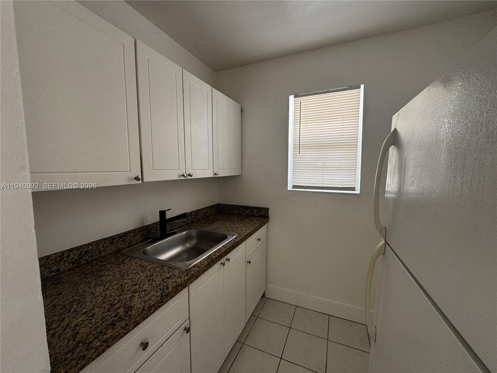 500 13th Street, Unit 10 Miami Beach, FL 33139 - Photo 7 of 12 a kitchen with granite countertop white cabinets and sink