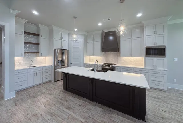 a large kitchen with kitchen island a sink stainless steel appliances and cabinets