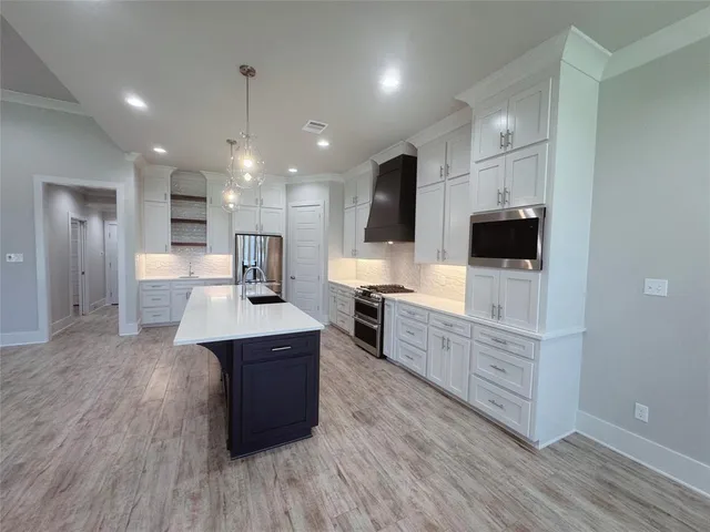 a large kitchen with stainless steel appliances a large counter top space wooden floor and a sink