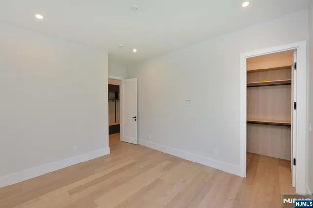 a view of an empty room with closet and wooden floor
