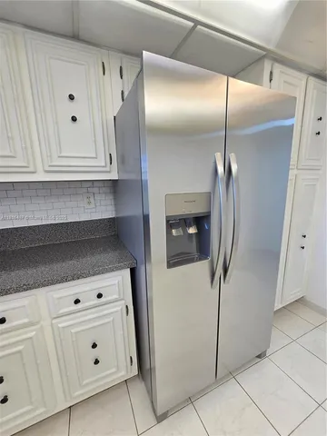 a large white kitchen with a sink and refrigerator