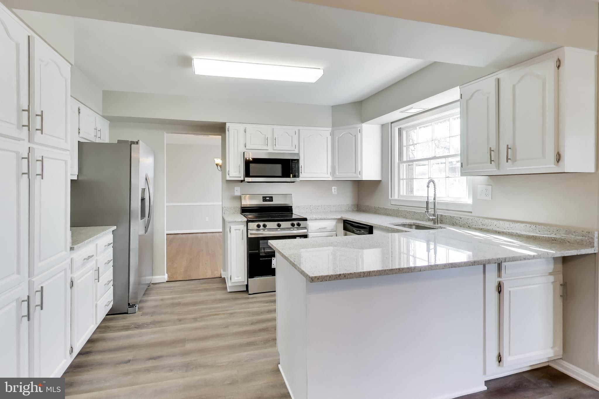 4007 Harrison Road Beltsville, MD 20705 - Photo 11 of 49 a kitchen with stainless steel appliances white cabinets a sink a stove a refrigerator and a window