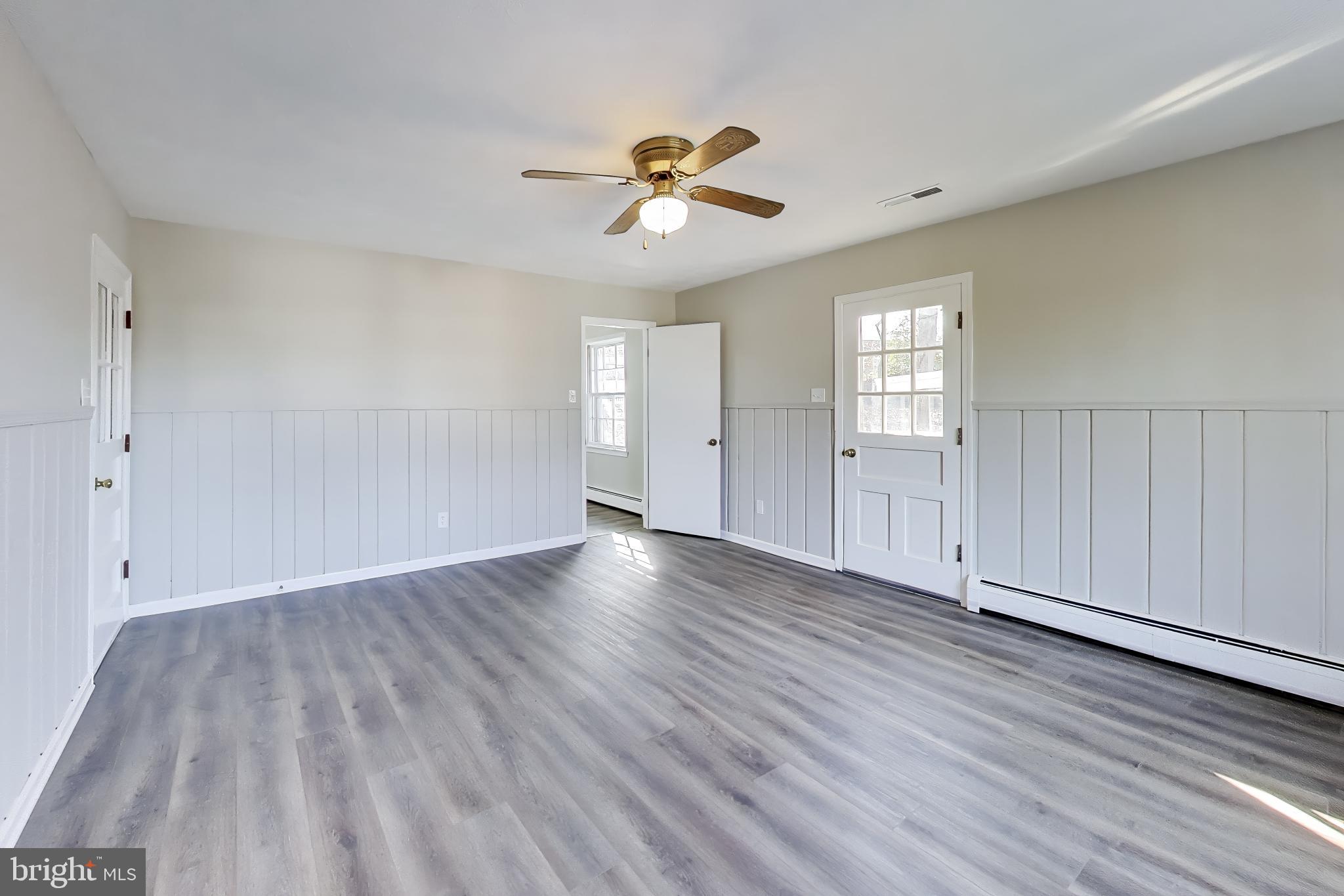 4007 Harrison Road Beltsville, MD 20705 - Photo 17 of 49 an empty room with wooden floor chandelier fan and windows