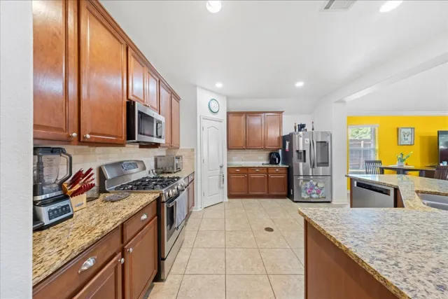 a large kitchen with stainless steel appliances granite countertop a stove refrigerator and microwave