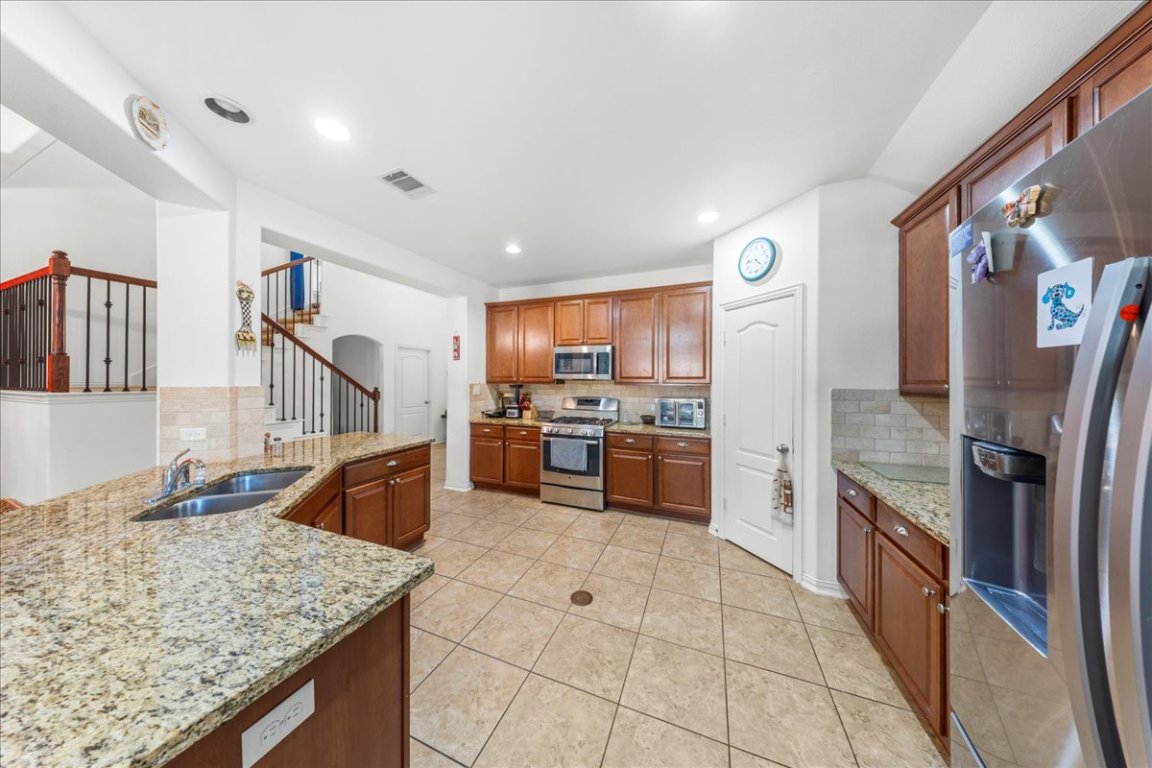 349 Razzmatazz Trail Buda, TX 78610 - Photo 27 of 40 a kitchen with stainless steel appliances granite countertop a refrigerator and a sink