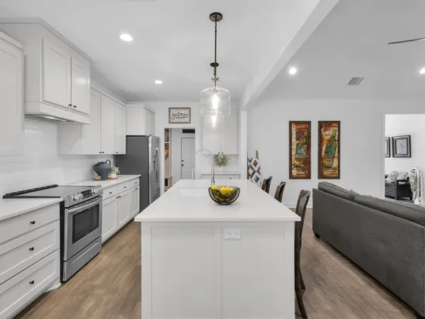 a kitchen that has a sink a stove and chairs
