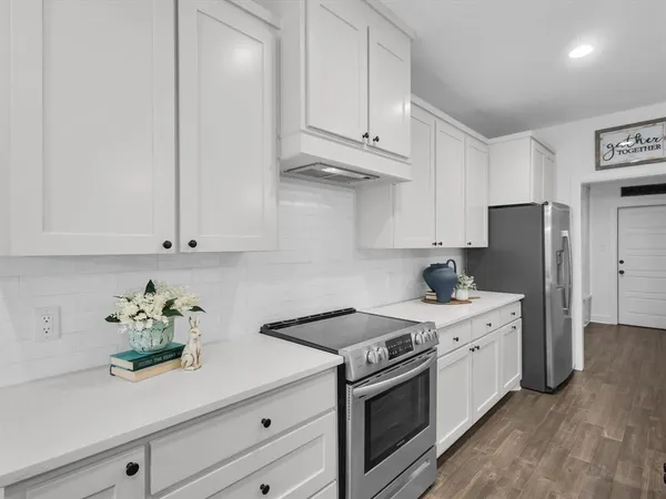 a kitchen with stainless steel appliances white cabinets and a stove top oven