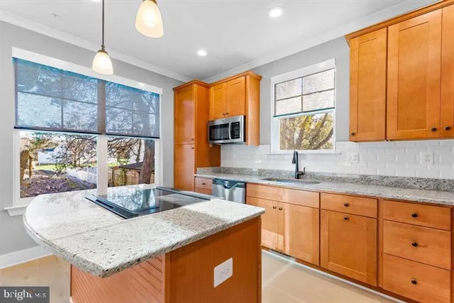 a kitchen with stainless steel appliances granite countertop wooden cabinets a sink and a large window