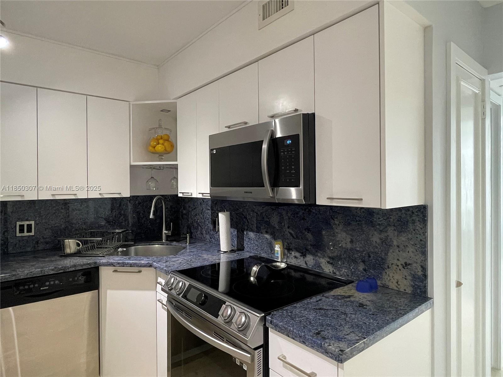5151 Collins Avenue, Unit 825 Miami Beach, FL 33140 - Photo 11 of 28 a kitchen with a sink a stove and cabinets