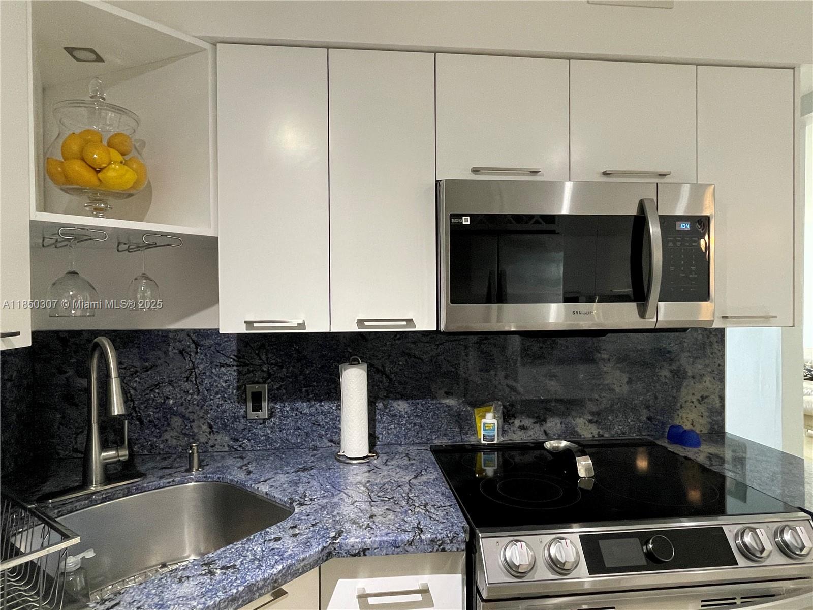 5151 Collins Avenue, Unit 825 Miami Beach, FL 33140 - Photo 12 of 28 a kitchen with a stove and a microwave