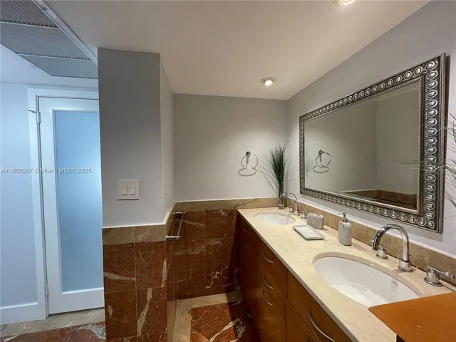 a bathroom with a granite countertop sink a mirror and a bathtub